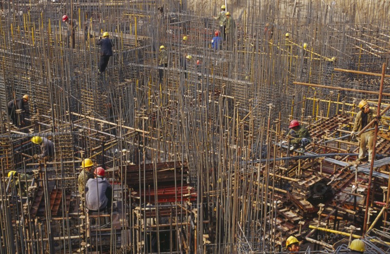 CHINA, Shaanxi Province, Xian, Construction workers on scaffolding amongst steel fixing on a building site.