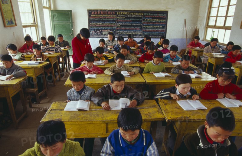 CHINA, Shaanxi Province, Xian, Classroom with school children reading at their desks with a teacher.