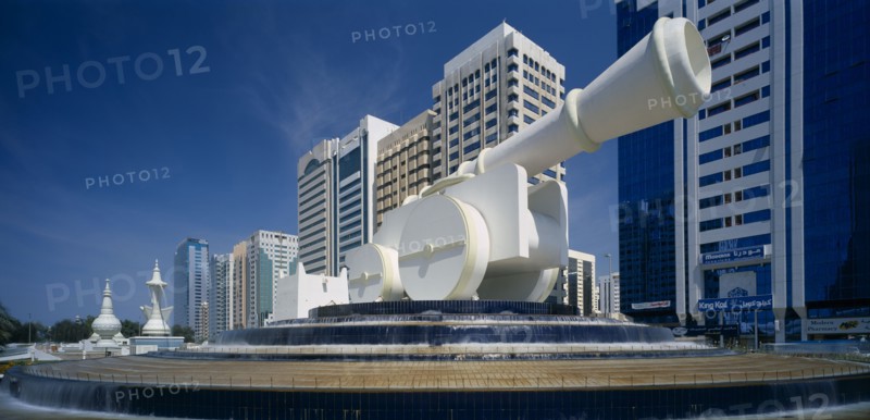 UAE, Abu Dhabi, Al-Ittihad Square with huge sculpture of a cannon set on a circular tiered waterfall with modern high rise buildings behind.