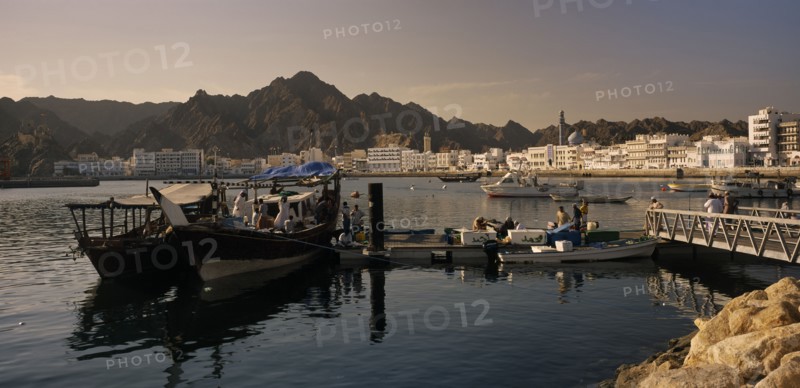 OMAN, Muscat, Mutrah Fish Market.  Fishing boats landing catch with waterside buildings behind.