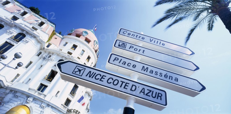 FRANCE, Provence-Cote d’Azur, Nice, "Promenade des Anglais.  Angled view of directional road sign in front of the Hotel Negresco, partly seen behind.  Alpes Maritimes"