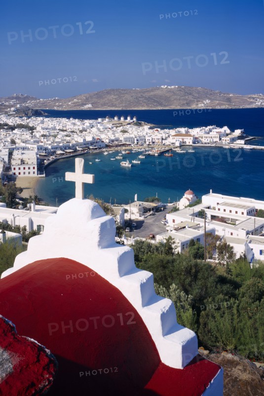 GREECE, Cyclades Islands, Mykonos, View over Mykonos town and harbour.  Part view of church roof in the foreground.