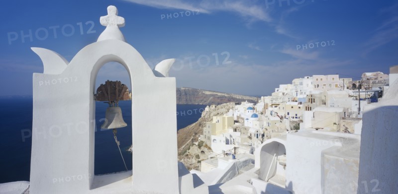 GREECE, Cyclades Islands, Santorini, Detail of white painted church bell tower with white painted hill town beind.