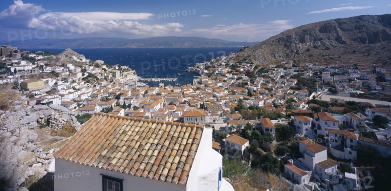 GREECE, Saronic Islands, Hydra, View over tiled rooftops of Hydra Town to harbour and distant coastline.