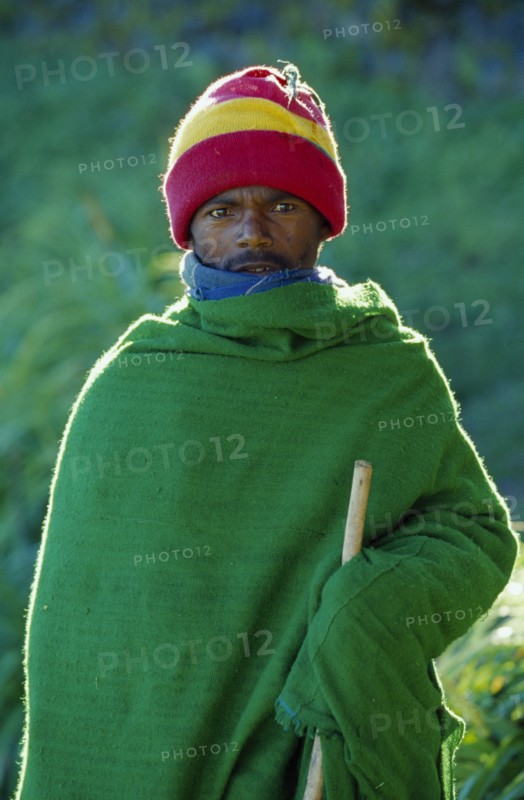 ETHIOPIA, Harerge Province, General, Portrait of young man wrapped in green woven blanket.