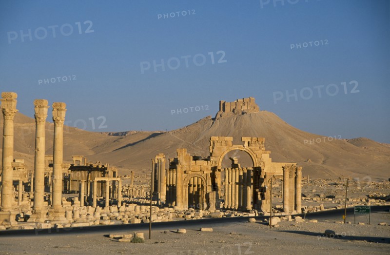 SYRIA, Central, Tadmur, View towards Monumental Arch comprising of high central arch flanked by a lower arch on each side with the Arab Castle or Qalaat Ibn Maan on the hilltop behind.