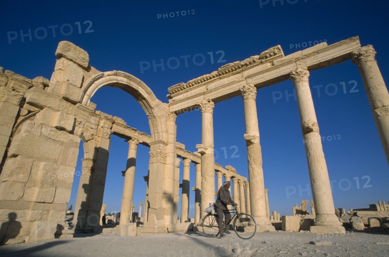SYRIA, Central, Tadmur, Colonnade and archway with man on a bicycle framed between columns.