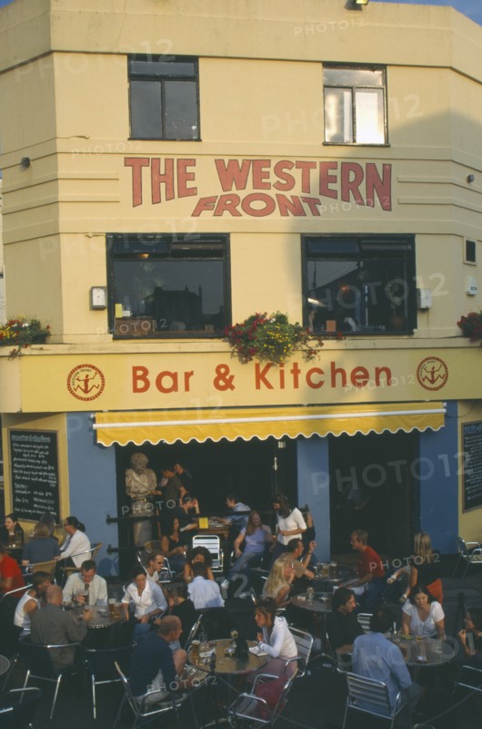ENGLAND, East Sussex , Brighton, City bar and restaurant with open front and people sitting at crowded outside tables.