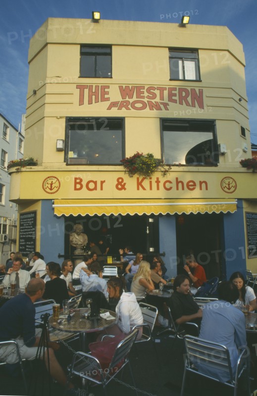 ENGLAND, East Sussex , Brighton, City bar and restaurant with open front and people sitting at crowded outside tables.