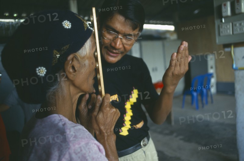 THAILAND, Tak Province, Mae Sot, Male optician giving an elderly woman an eye test at the Mae Tao Clinic.