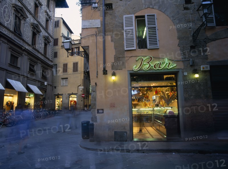 ITALY, Tuscany, Florence, Ice cream bar with neon sign illuminated at night in narrow street with pedestrians in blurred movement.