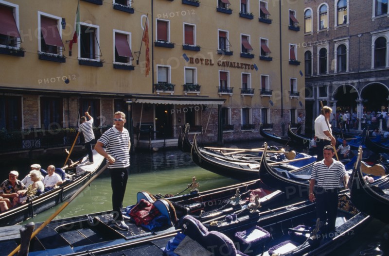 ITALY, Veneto, Venice, "Gondolas tied up at Hotel Cavalletto, with gondolier and tourist passengers partly seen behind.  "