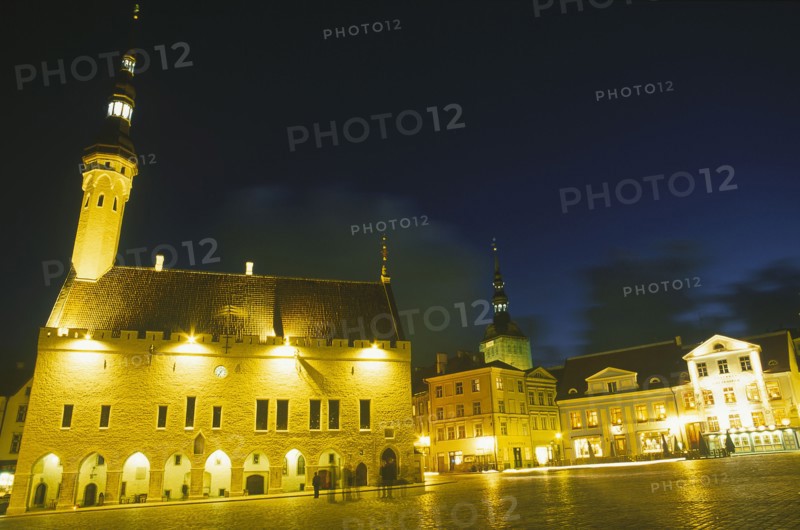 ESTONIA, Tallinn, Raekoja Plats.  Exterior of the town hall and nearby shops and restaurant illuminated at night.