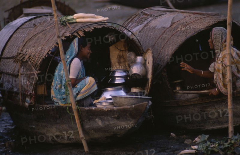 20017896 BANGLADESH  Transport Two female river gypsies in covered wooden boats talking to each other.