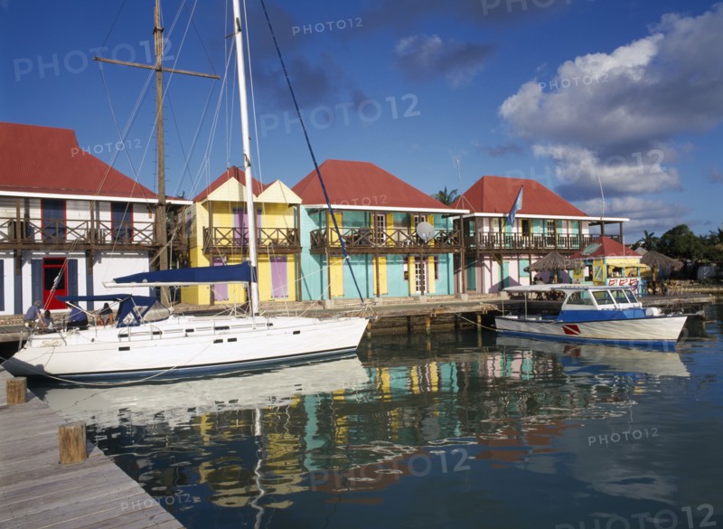 WEST INDIES, Antigua, St Johns, "Redcliffe Quay.  Area of restored historical buildings, boats moored at wooden jetty with line of buildings with colourfully painted facades behind."
