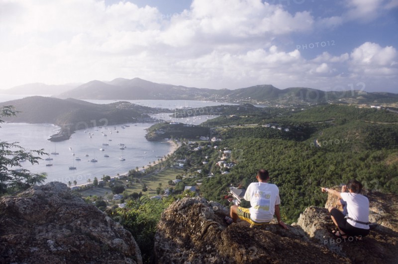 WEST INDIES, Antigua, General, Couple sitting on rocks on hillside above Ordnance bay on the right and Tank Bay on the left.