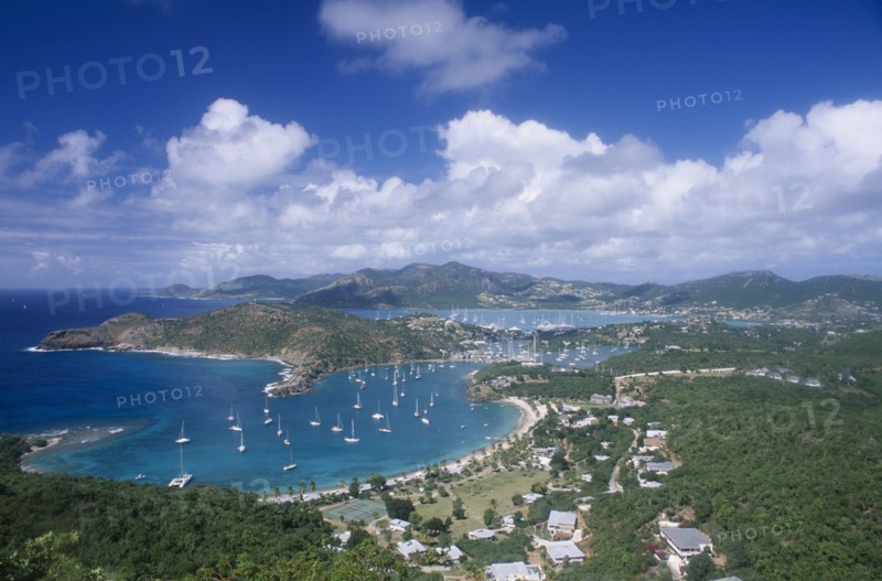 WEST INDIES, Antigua, English Harbour, View over harbour and surrounding area with scattered housing and tree covered hillside.