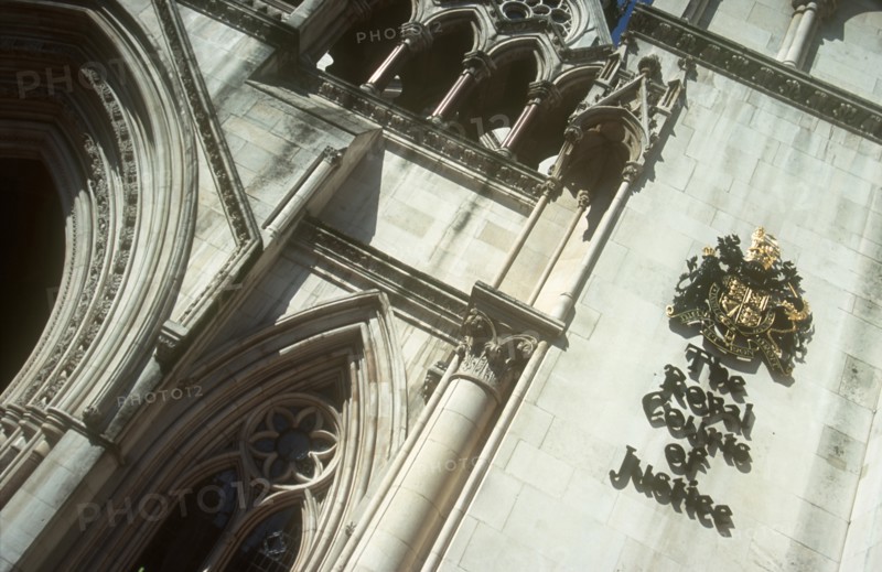 ENGLAND, London, Royal Courts of Justice. View looking up at the building with the crest displayed on the wall.