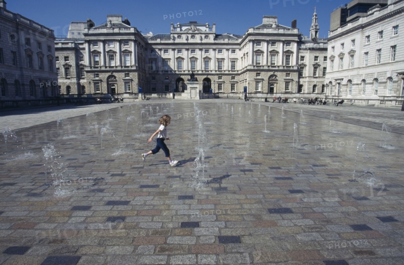 ENGLAND, London, Somerset House and courtyard with rows of small fountains spouting from the ground with a girl running between them.