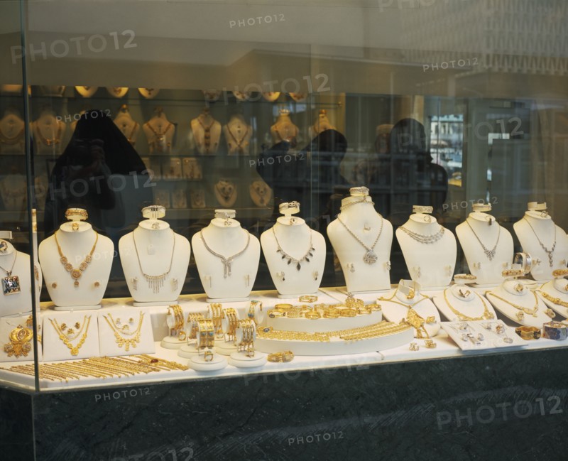 KUWAIT, Kuwait City , "Gold Souq.  Three women in black Burqa inside jewellery shop, seen through window with display  of gold and silver."