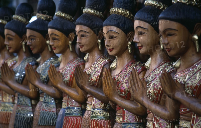 THAILAND, North, Chiang Mai, Loi Kroh. Traditional wooden carvings of women outside a crafts shop
