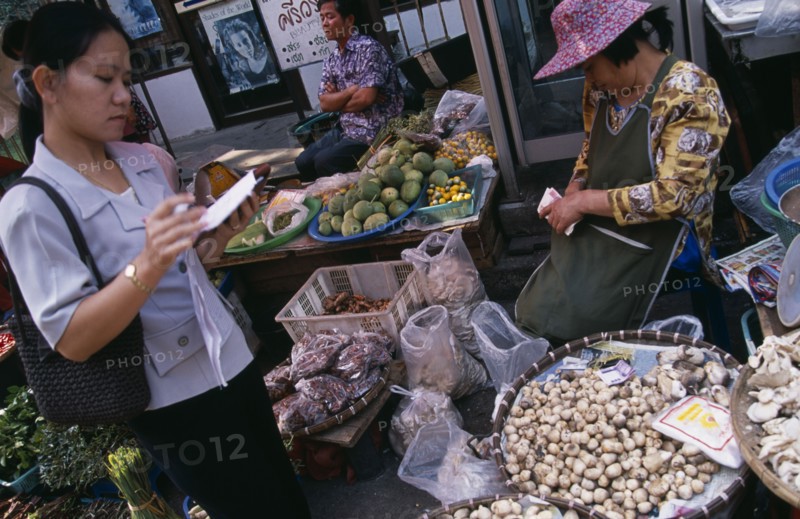 THAILAND, North, Chiang Mai, Wholesale Food Market.  Female buyer for restaurant purchasing mushrooms from vendor.