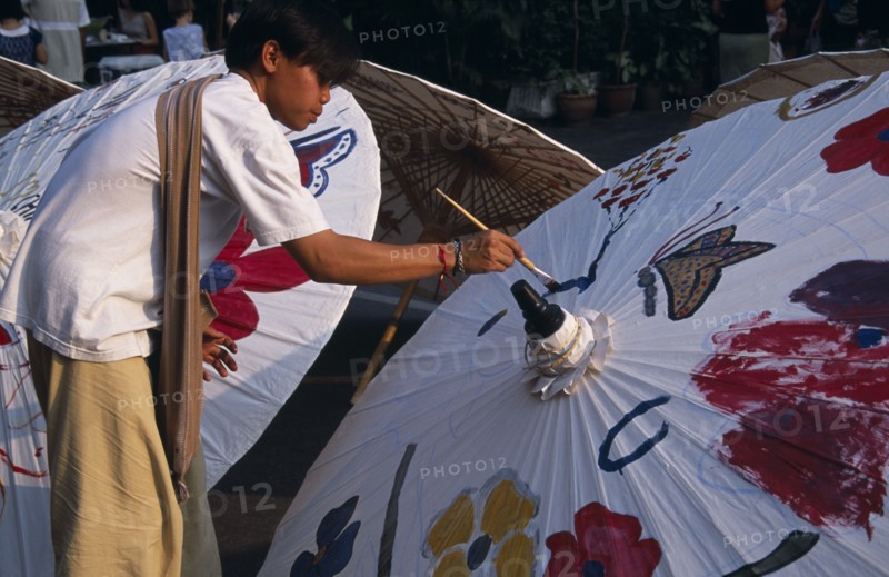 THAILAND, North, Chiang Mai, Tha Phae Road.  Young man taking part in umbrella painting competition on a sunday when the road is closed to traffic.