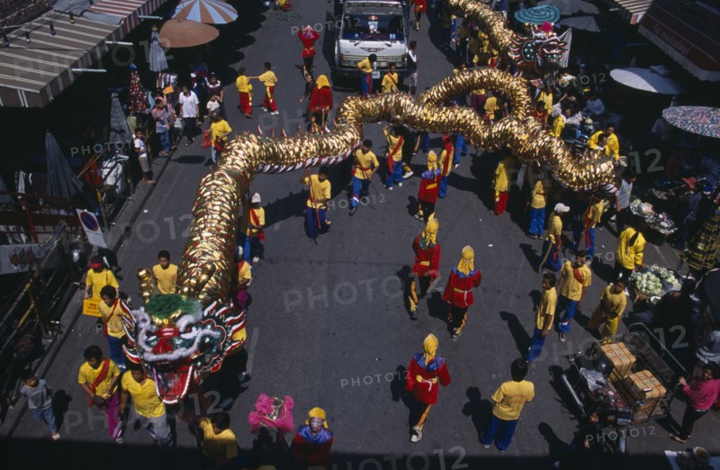 20021755 THAILAND North Chiang Mai Chinese New Year.  View looking down on Dragon Dance and watching crowds under striped awning and sun umbrellas lining road.