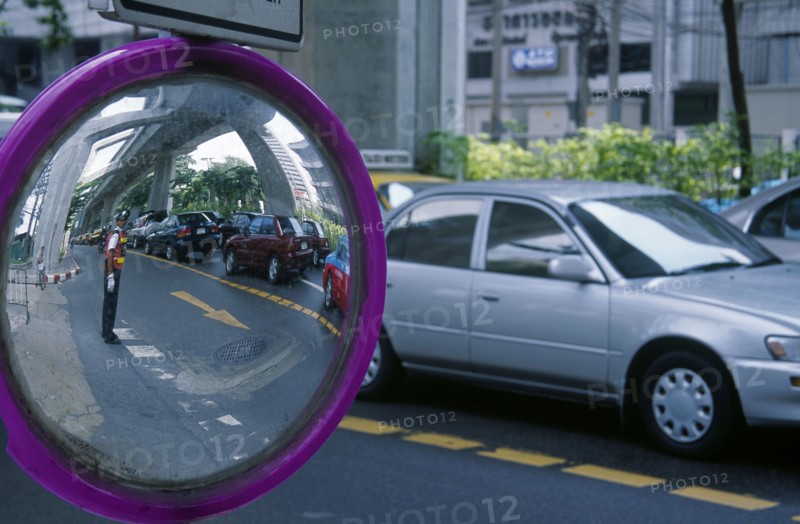 THAILAND, Bangkok, Transport, Roadside mirror reflecting traffic policeman with passing traffic.
