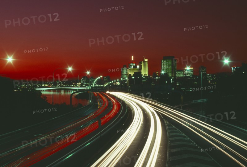 AUSTRALIA, Queensland, Brisbane, The south east freeway approaching the city illuminated at night with red and white traffic light trails.