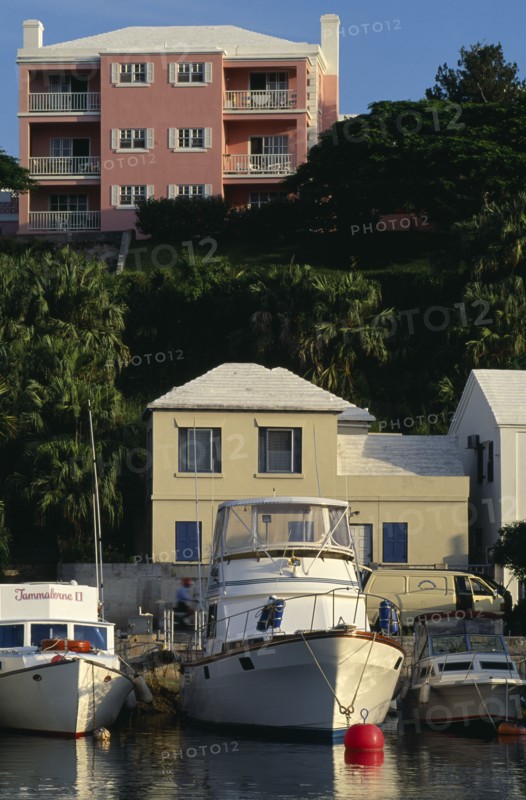 BERMUDA, Flatts Village, Pink building with white shutters and balconies overlooking boats moored in the water below.