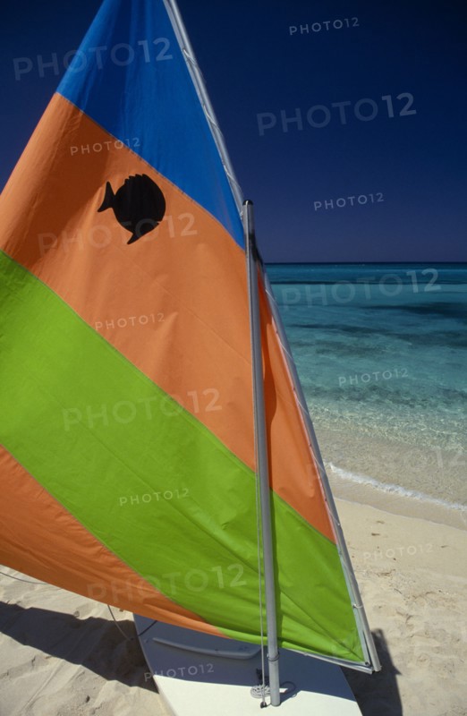 WEST INDIES, Jamaica, Transport, "Sail board with colourful, striped sail pulled up on sandy beach with sea behind."