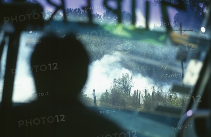 MEXICO, Near Angangueo, Burning stubble as seen from inside a Super Bus with man silhouetted.
