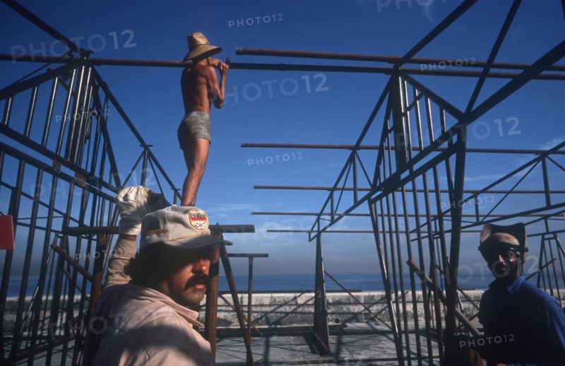 CUBA, Havana, Construction workers erecting metal framework for stalls during the Carnival on the Malecon
