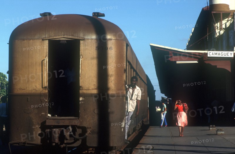 CUBA, Camaguey, Railway carriages alongside the platform of Camaguey station with a man holding onto a carriage door with a woman walking past