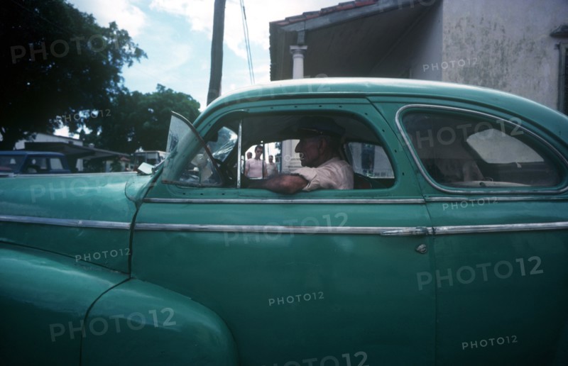 CUBA, Havana, Man driving a light green 1950 s car