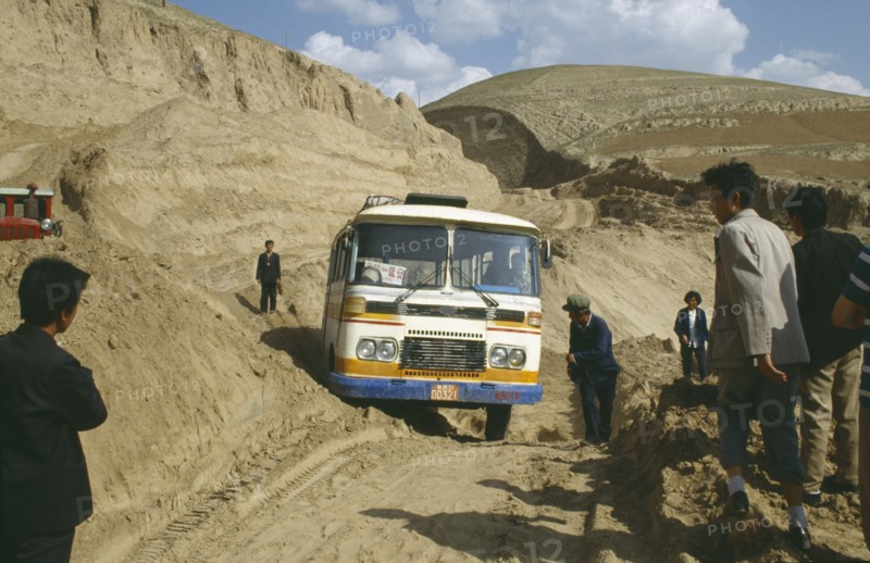 CHINA, Shaanxi , Bus stuck in earth along the main road with people standing by the sides of the dirt track