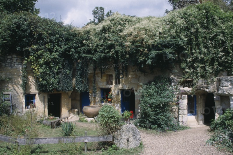 FRANCE, Loire, Les Maisons Trogladytes / La Fosse de Forges. Old style cottages rooved by overhanging trees and ivy.