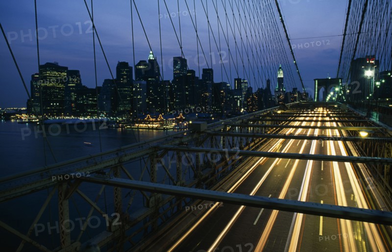 USA, New York, New York City, Brooklyn Bridge with speeding traffic headlights at night