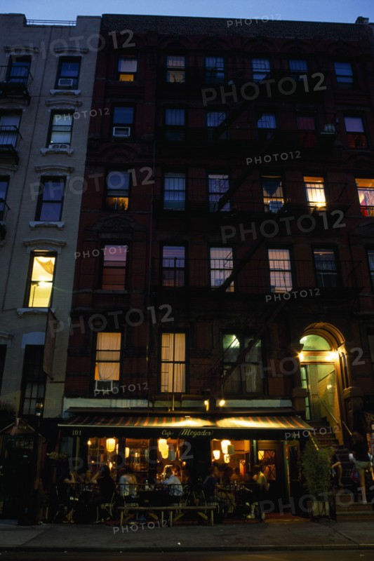 USA, New York, New York City, East Village. Cafe Mogador with tables and chairs under awning and apartments above