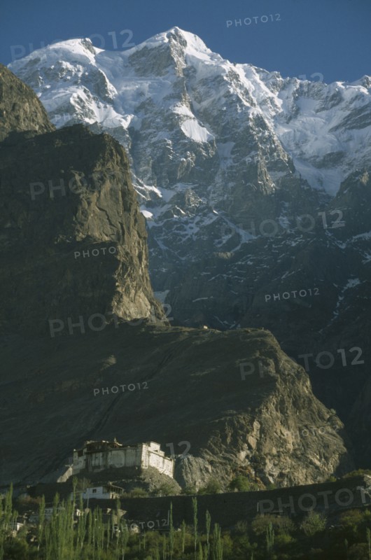 PAKISTAN, Northern Areas, Hunza Valley, "Baltit  Fort built on a cliff side with snow covered peaks of Ultar Sar mountain behind.  Original foundations thought to be 800 years old, restoration completed in 1996."
