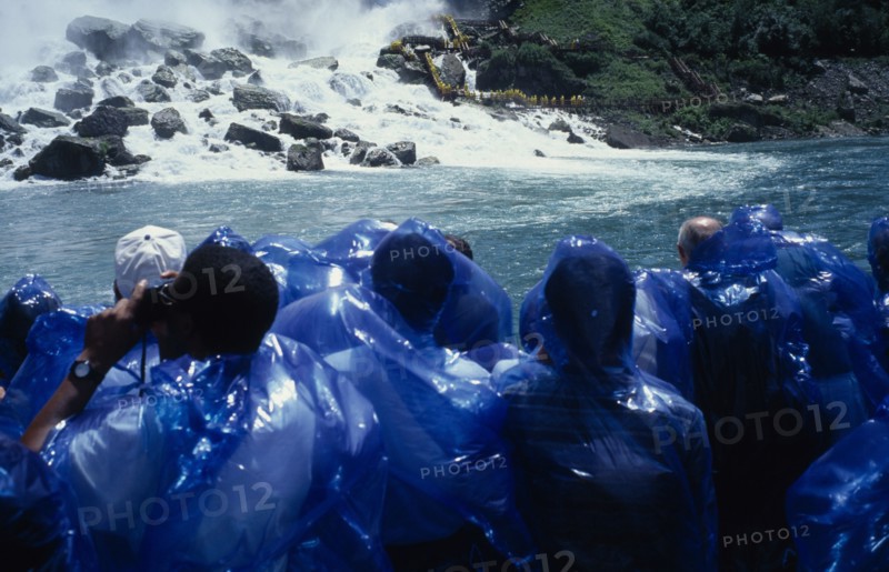 CANADA, Ontario, Niagara Falls, Maid of the Mists tourists in blue waterproofs looking toward American Falls