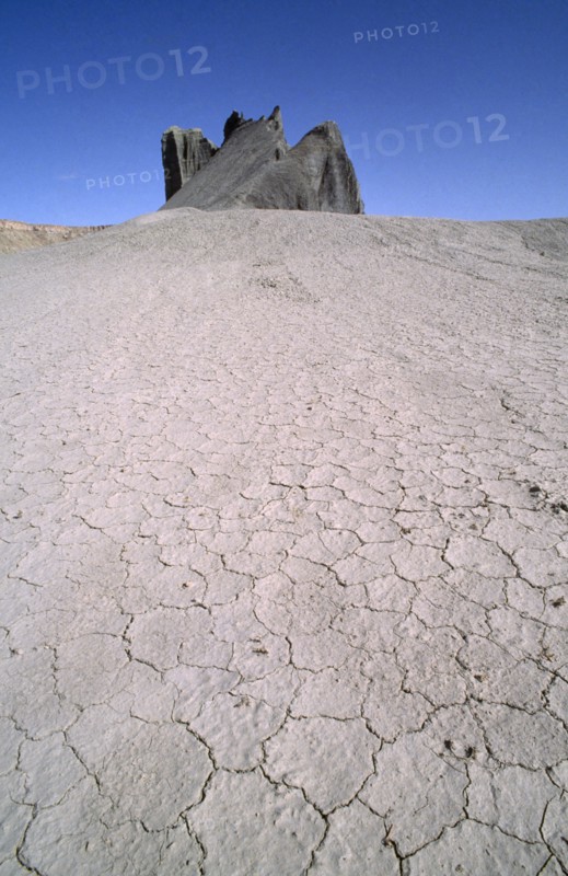 USA, Utah, North Pinto Hills, View over cracked dry earth toward rock formation on the horizon