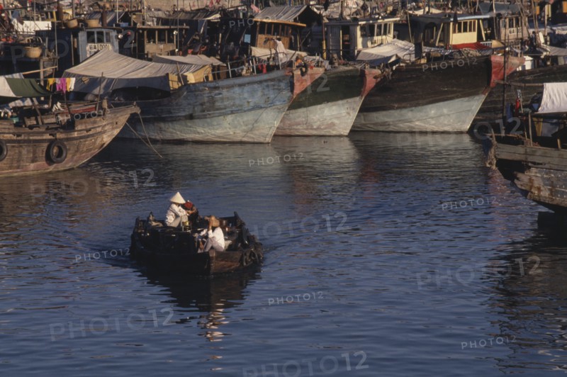CHINA, Hainan Island , Sanya, People in a small motor boat passing in front of fishing boats moored in the harbour