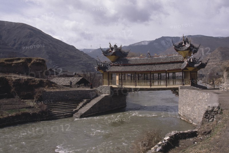 CHINA, Sichuan Province, Songpan, Chinese bridge with pagoda style roof over river in mountain landscape