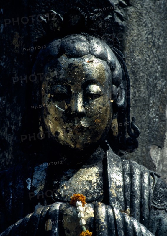 THAILAND, Bangkok, Wat Phra Kaew, Or Royal Palace. Close up detail of golden statue with floral arrangement placed on her clasped hands