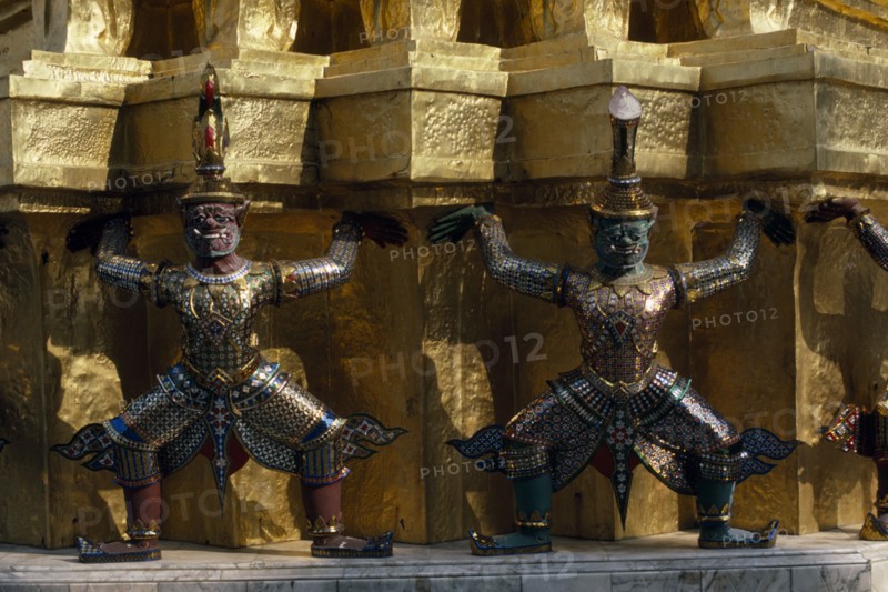 THAILAND, Bangkok, Grand Palace, Wat Phra Kaew. Detail of elaborate exterior with statues supporting golden walls