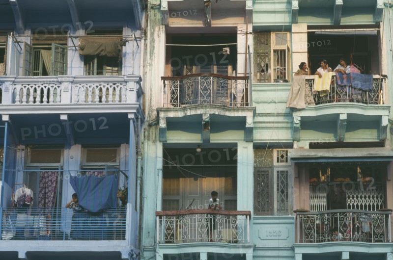MYANMAR, Yangon, Building detail of balconies with hanging washing and people standing