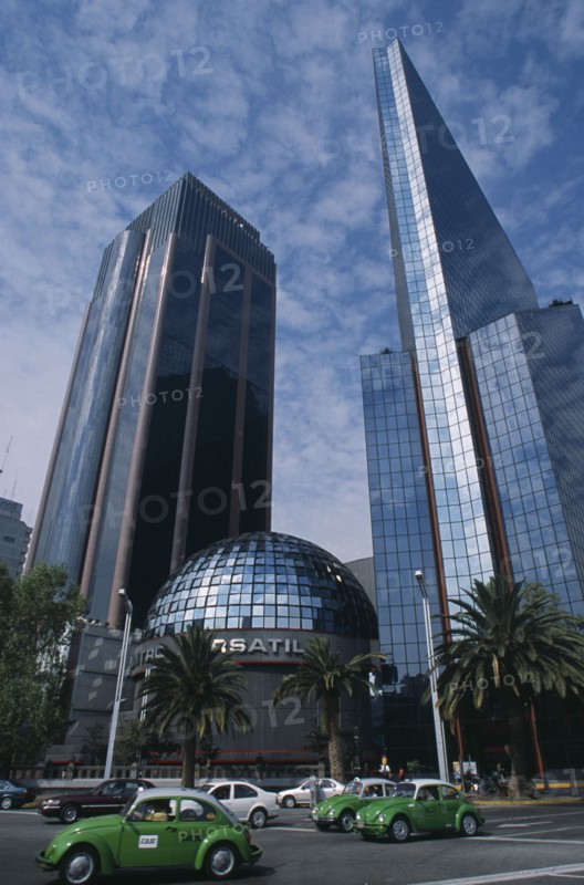 MEXICO, Mexico City, "Financial district in Zona Rosa on Paseo de La Reforma.  Domed roof of bank surrounded by high rise buildings, green volkswagon taxis on road in the foreground. "