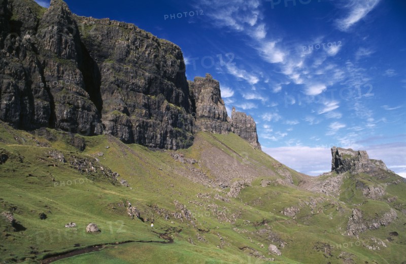 SCOTLAND, Isle of Skye, North, Quiraing Escarpment Mountains with walker on lower slopes.